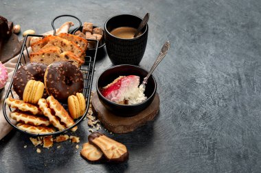 Lezzetli kurabiyeli beyaz kahve, çörek, kek, şeker, waffle. Karanlık arka planda şekerli sıcak içecek. Boşluğu kopyala.