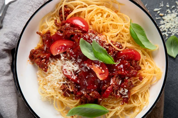 stock image Tasty appetizing classic italian spaghetti bolognese pasta with tomato sauce, cheese parmesan, meat and basil on plate on a dark background. Top view.