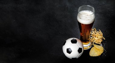 Siyah arka planda futbol topu olan bira ve atıştırmalıklar. Futbol maçı gece yemeği.. 