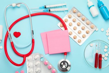 Çeşitli tıbbi ekipmanlar, ampuller, pipet, ilaçlar, haplar, kapsüller, mavi arka planda sprey. Üst görünüm.