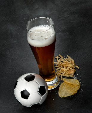 Siyah arka planda futbol topu olan bira ve atıştırmalıklar. Futbol maçı gece yemeği.. 