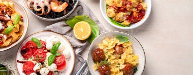 Tabaklar dolusu İtalyan yemeği pizza, makarna, ravioli, caprese salatası ve beyaz arka planda domates bruschetta. Üst Manzara. Kopyalama alanı olan Panorama.