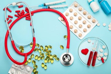 Çeşitli tıbbi ekipmanlar, ampuller, pipet, ilaçlar, haplar, kapsüller, mavi arka planda sprey. Üst görünüm.