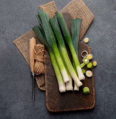 Koyu bir arka planda taze pırasa, vejetaryen yemeği, sağlıklı beslenme. Üst görünüm.