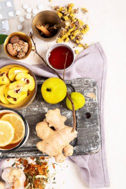 Soğuk algınlığı ve grip virüsü için doğal şifalı bitkisel ilaç. Taze zencefil, limon, bal ve tarçınla birlikte sıcak içecek. Beyaz arka planda ekinezya, dikenli çilek ve ginseng. Bağışıklık güçlendirici. Boşluğu kopyala.