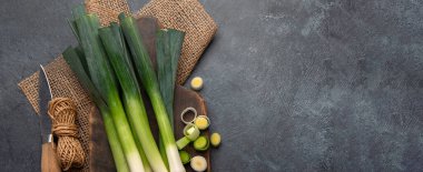 Koyu bir arka planda taze pırasa, vejetaryen yemeği, sağlıklı beslenme. Üst Manzara. Kopyalama alanı olan Panorama.