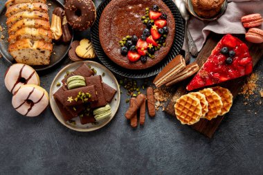 Lezzetli pasta, kurabiye, waffle, badem kurabiyesi, kek. Koyu arkaplanda lezzetli tatlılar. Yemek konsepti. Üst görünüm