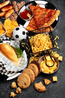 Doymuş yağlar. Futbol zamanı. TV uzaktan kumandası ve atıştırmalıklar - cips, patlamış mısır, kurabiye, peynir, sos, patates kızartması, hamburger, fındık. Üst görünüm