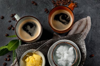 Kurşun geçirmez keto kahvesi. Ketogenik diyet. Hindistan cevizi yağı ve koyu arkaplanda yağ ile sıcak kurutma. Üst görünüm