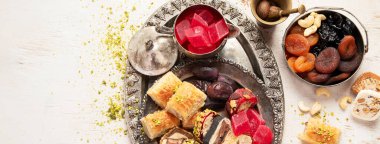 Baklava, halva, rahat lokum, fındık, fıstık, hurma, kuru üzüm, kayısı, kilise. Geleneksel doğu tatlıları, Arap tatlıları, beyaz arka planda Türk tatlıları. Üst Manzara. Kopyalama alanı olan Panorama.