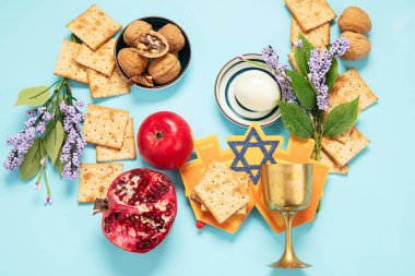 Hamursuz Bayramı kutlaması konsepti. Matzah, kırmızı kaşer cevizi ve mavi arka planda bahar çiçekleri. Geleneksel Yahudi ekmeği. 