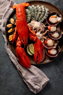 Taze ıstakoz, midye ve istiridye içeren deniz ürünleri tabağı. Karanlık bir arka planda okyanus gurmesi olarak. Üst görünüm.