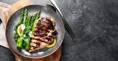 Izgara tavuk göğsü ve koyu arkaplanda kuşkonmaz. Üst Manzara. Kopyalama alanı olan Panorama.