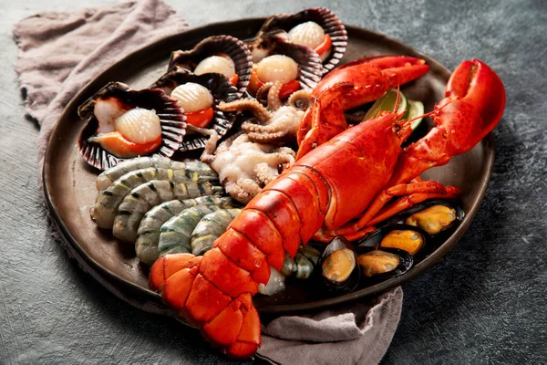 Taze ıstakoz, midye ve istiridye içeren deniz ürünleri tabağı. Karanlık bir arka planda okyanus gurmesi olarak. Üst görünüm.