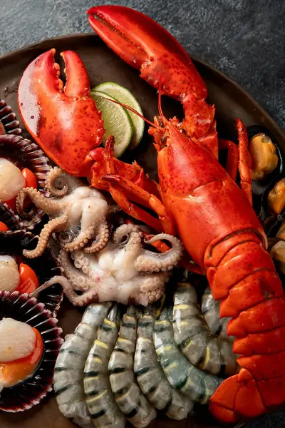 Taze ıstakoz, midye ve istiridye içeren deniz ürünleri tabağı. Karanlık bir arka planda okyanus gurmesi olarak. Üst görünüm.