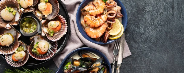 Koyu arkaplanda, siyah taş bir tabakta, soslu ve baharatlı deniz kabuklarıyla pişirilmiş deniz tarakları. Deniz ürünleri. Üst Manzara. Kopyalama alanı olan Panorama.