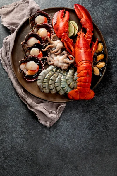 Taze ıstakoz, midye ve istiridye içeren deniz ürünleri tabağı. Karanlık bir arka planda okyanus gurmesi olarak. Üst Manzara. Boşluğu kopyala.