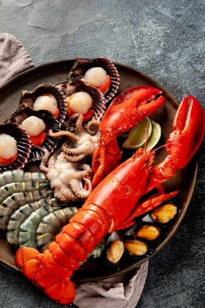 Taze ıstakoz, midye ve istiridye içeren deniz ürünleri tabağı. Karanlık bir arka planda okyanus gurmesi olarak. Üst görünüm.