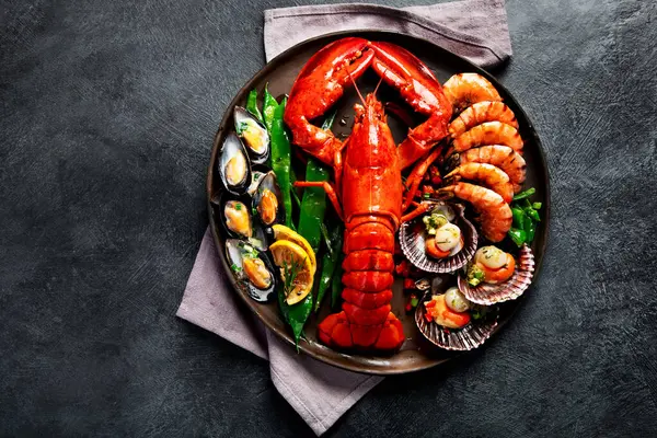 Tabakta büyük kırmızı ıstakoz, karides ve limonlu midye, kıtır sos ve ekmek. Deniz ürünleri konsepti. Üst görünüm.