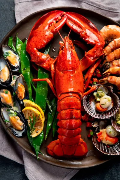 Tabakta büyük kırmızı ıstakoz, karides ve limonlu midye, kıtır sos ve ekmek. Deniz ürünleri konsepti. Üst görünüm.