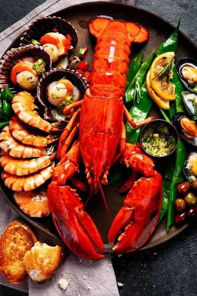 Tabakta büyük kırmızı ıstakoz, karides ve limonlu midye, kıtır sos ve ekmek. Deniz ürünleri konsepti. Üst görünüm.