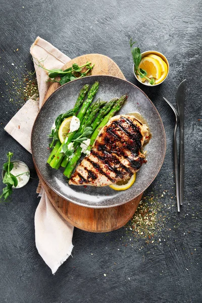 Izgara tavuk göğsü ve koyu arkaplanda kuşkonmaz. Üst görünüm.