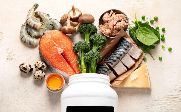 Beyaz zemin üzerinde doğal D vitamini kaynakları (Balık, peynir, yumurta, mantar, karides). Üst görünüm.