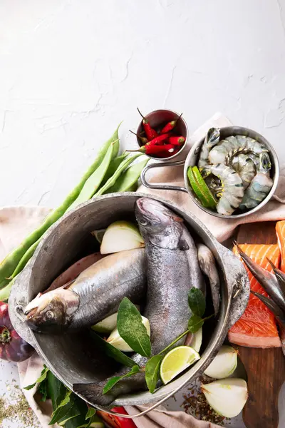 Fish with aromatic herbs, spices and vegetables - healthy food, diet or cooking concept on a white background. Top view. Copy space.