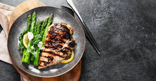 Izgara tavuk göğsü ve koyu arkaplanda kuşkonmaz. Üst Manzara. Kopyalama alanı olan Panorama.