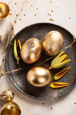 Altın yumurta paskalya konsepti. Hafif arka planda çiçekli Paskalya altın yumurtaları. Mutlu Paskalyalar. Üst görünüm.