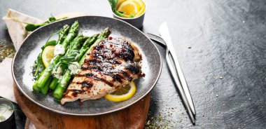 Izgara tavuk göğsü ve koyu arkaplanda kuşkonmaz. Üst Manzara. Kopyalama alanı olan Panorama.