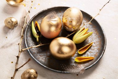 Altın yumurta paskalya konsepti. Hafif arka planda çiçekli Paskalya altın yumurtaları. Mutlu Paskalyalar. Üst görünüm.