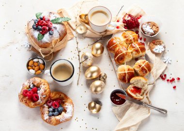 Beyaz arka planda çeşitli ekmekler, tatlılar ve ikramlar içeren Paskalya masası sahnesi. Üst Manzara. Bahar tatili yemekleri..