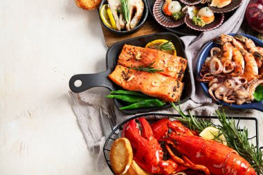 Hafif ahşap arka planda deniz ürünleri tabakları. Üst görünüm, alanı kopyala