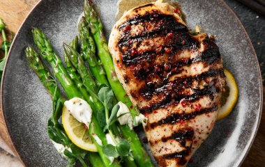 Izgara tavuk göğsü ve koyu arkaplanda kuşkonmaz. Üst görünüm.