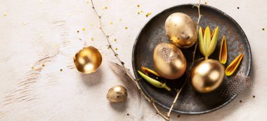 Altın yumurta paskalya konsepti. Hafif arka planda çiçekli Paskalya altın yumurtaları. Mutlu Paskalyalar. Üst Manzara. Kopyalama alanı olan Panorama.