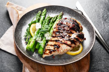 Izgara tavuk göğsü ve koyu arkaplanda kuşkonmaz. Üst görünüm.