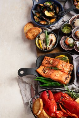 Hafif ahşap arka planda deniz ürünleri tabakları. Üst görünüm, alanı kopyala