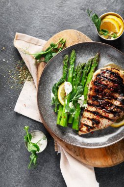 Izgara tavuk göğsü ve koyu arkaplanda kuşkonmaz. Üst görünüm.