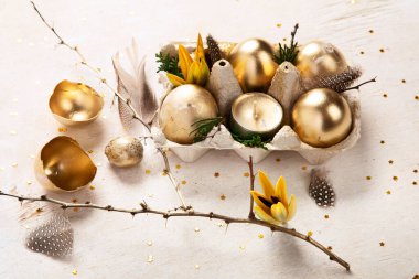 Altın yumurta paskalya konsepti. Hafif arka planda çiçekli Paskalya altın yumurtaları. Mutlu Paskalyalar. Üst görünüm.