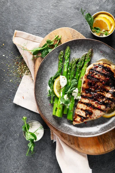 Izgara tavuk göğsü ve koyu arkaplanda kuşkonmaz. Üst görünüm.