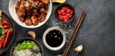 Koyu arkaplanda tavuklu teriyaki soslu, pilav, sebze ve susam tohumlu. Asya yemekleri. Üst Manzara. Kopyalama alanı olan Panorama.