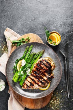 Izgara tavuk göğsü ve koyu arkaplanda kuşkonmaz. Üst Manzara. Boşluğu kopyala.