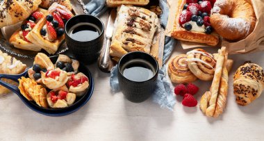 Arka planda çeşitli hamur işleri ve kahve fincanları olan masa. Üst Manzara. Boşluğu kopyala.