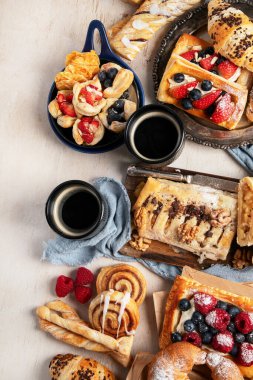 Arka planda çeşitli hamur işleri ve kahve fincanları olan masa. Üst Manzara. Boşluğu kopyala.