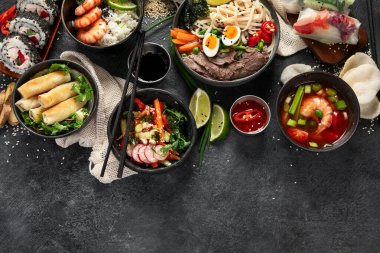 Geleneksel Asya yemek masası. Çin böreği, pirinç, karides, suşi, sebze, arka planda et. Üst görünüm, alanı kopyala