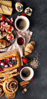 Farklı lezzetlerde, koyu arkaplanda yeni pişmiş hamur işleri. Üst Manzara. Kopyalama alanı olan Panorama.