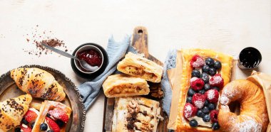 Arka planda çeşitli hamur işleri ve kahve fincanları olan masa. Üst Manzara. Kopyalama alanı olan Panorama.