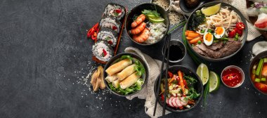 Geleneksel Asya yemek masası. Çin böreği, pirinç, karides, suşi, sebze, arka planda et. Üst görünüm, kopyalama alanı, afiş