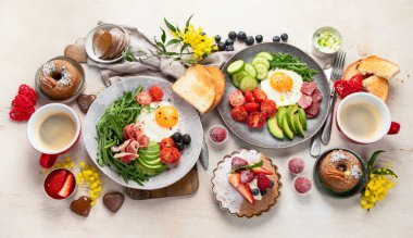 Kahvaltının yanında kahve, fırın, yumurta, salata, et ve meyve var. Tatil konsepti. Üst görünüm.